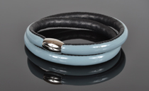 Armbånd i lys blå lak læder og sort kalveskind. 2 omgange med magnetlås i stål. Tykkelse 7,5 mm.